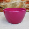 Bright pink Ceramic Garden Bowl displayed on a light surface with a blurred stone and brick wall, suitable as an indoor or outdoor planter.