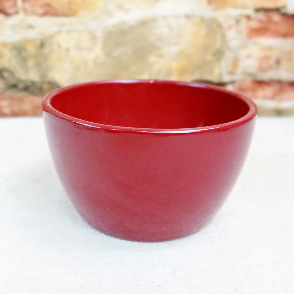 Ceramic Garden Bowl in 9 colors shown on a light surface, with a blurred stone and brick wall, ideal for indoor or outdoor plants.