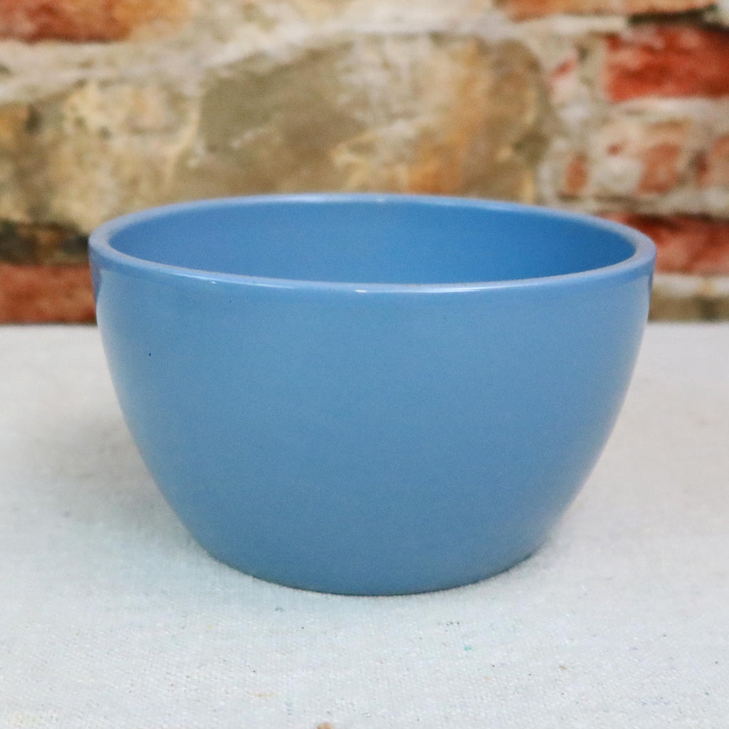 Blue Ceramic Garden Bowl placed on a light surface with a brick and stone wall in the background, suitable for indoor or outdoor use.