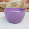 Purple Ceramic Garden Bowl displayed on a light surface, set against a blurred stone and brick wall; suitable for indoor or outdoor plants.