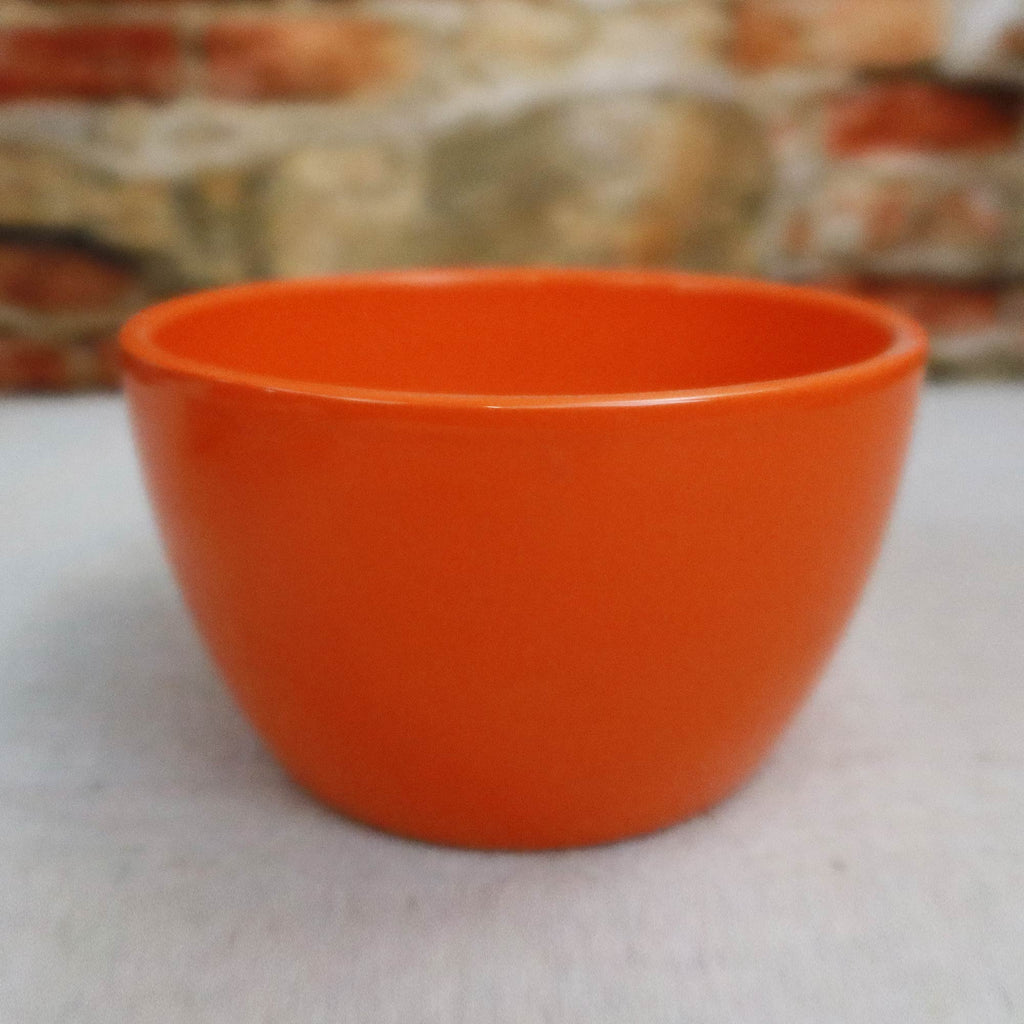 Orange Ceramic Garden Bowl displayed on a light surface with a blurred stone and brick wall background, suitable as an indoor-outdoor planter.