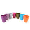 Seven glossy ceramic cups in purple, lavender, gray, pink, green, blue, and orange arranged in a row like planters on white background.