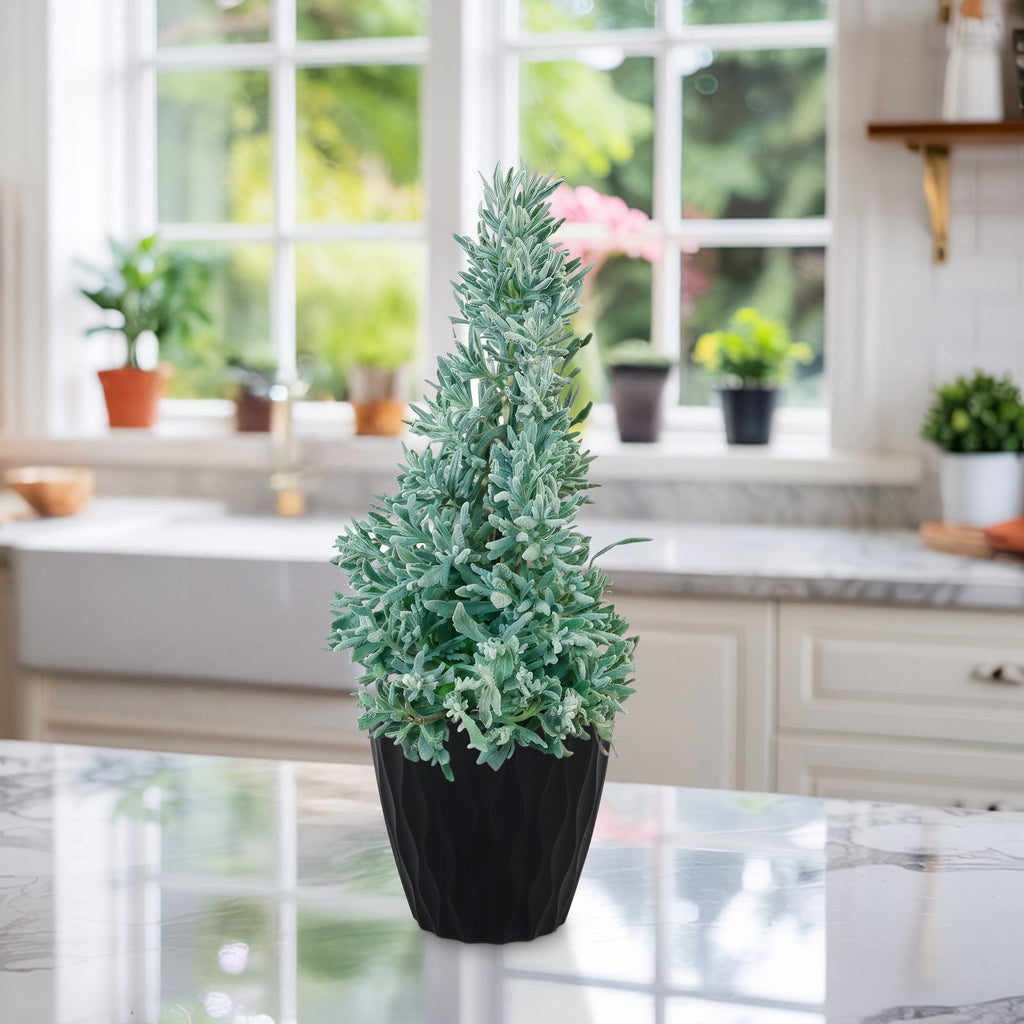 A small Lavender Christmas Tree with light green artificial foliage sits on a marble countertop in a bright kitchen alongside other plants.